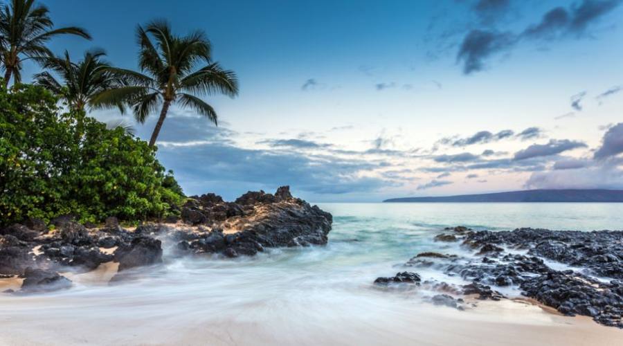 Waves crashing on the beach of Secret cove at dawn on Maui